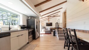 Una cocina moderna con armarios blancos, un refrigerador de acero inoxidable y una mesa de comedor de madera con sillas.