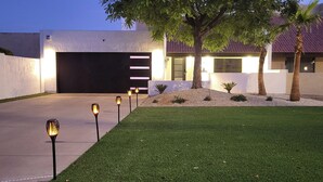 A modern house with a well-maintained lawn, a garage, and a tree.