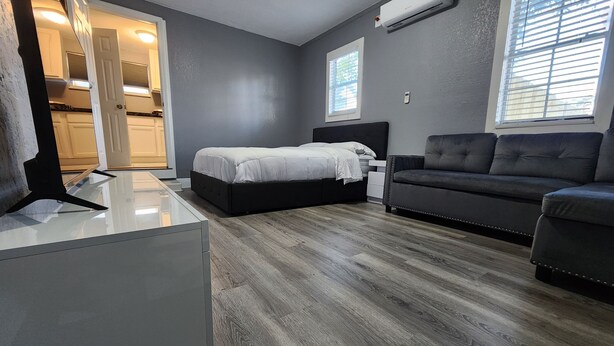 A modern bedroom with a bed, a sofa, and a desk.