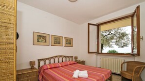 A bedroom with a bed, a chair, a window, and three framed pictures on the wall. - Nice apartment for 6 people with pool, WIFI, TV and terrace (Torri Del Benaco)