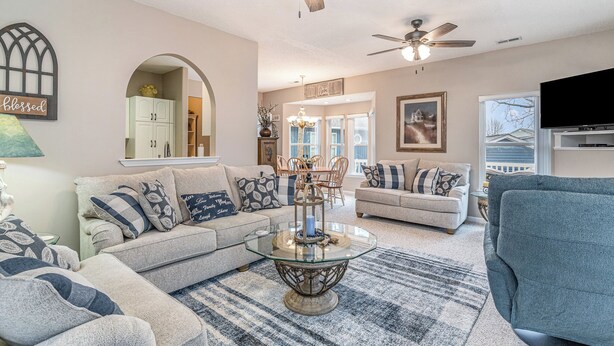 A living room with a sectional sofa, a glass coffee table, and a ceiling fan. - 7028 Ocean Lakes Golf Cart⛱️🏝️🩱🌊👙☀️🐚 (Myrtle Beach)