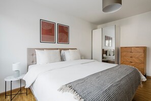 A modern bedroom with a large bed, a bedside table with a lamp, and a wardrobe. - Blueground | Matthäus, balcony & w/d, nr zoo (Basel)