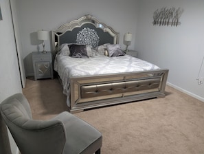 Ein Schlafzimmer mit einem Bett, zwei Nachttischen, einem Sessel und einem Wandbild.