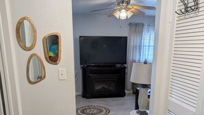 A living room with a television, a ceiling fan, and a fireplace.
