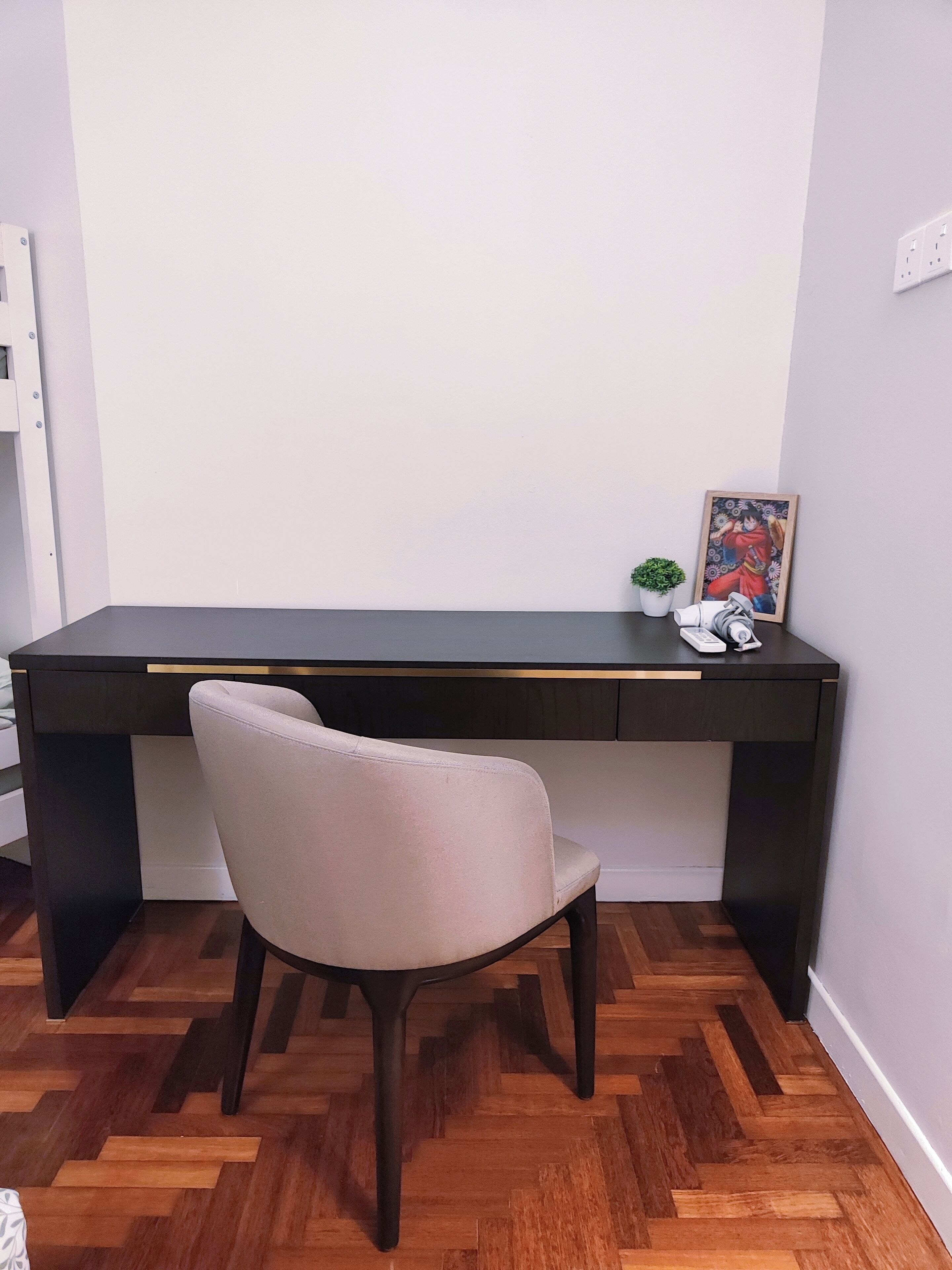 A modern desk with a chair, a framed picture, and a small plant.