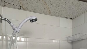 A shower with white tiles and a metal shower head.