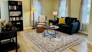 Un soggiorno con divano, tavolino, libreria e tappeto decorato.