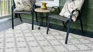 Un portico con due sedie, un tavolino rotondo e un vaso decorativo.