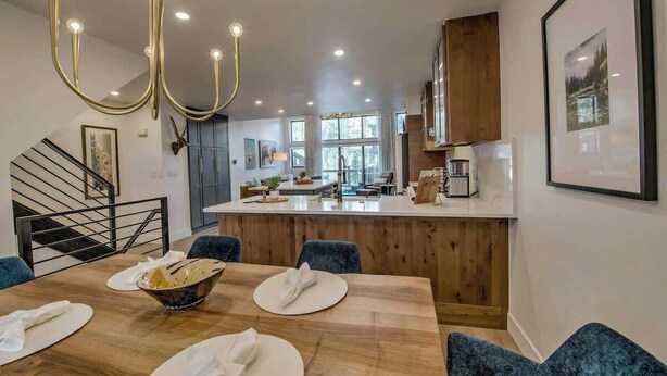 A modern kitchen with a central island, wooden cabinets, and a chandelier.