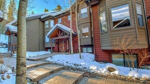 A multi-story residential building with a snow-covered exterior, a stone pathway leading to the entrance, and a clear sky.