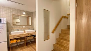 Een moderne badkamer met twee wastafels, een spiegel en een houten trap.