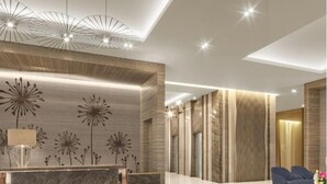 A modern lobby with a reception desk, seating area, and decorative wall panels. - 2 BR Fully Furnished Condo Parañaque with Pool and Parking - Bloom 1133 (Parañaque)