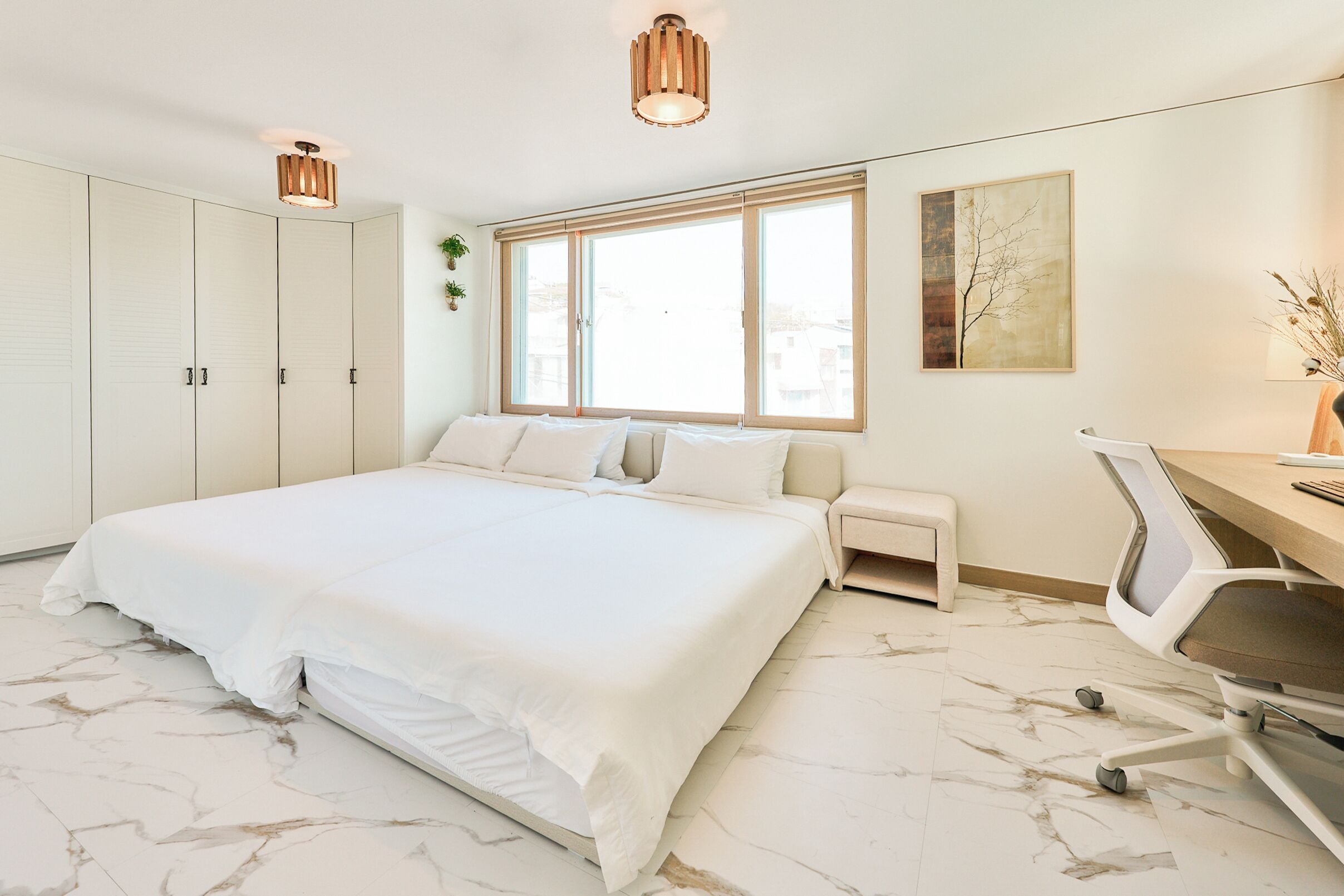 A modern bedroom with a large bed, a desk, and a window.