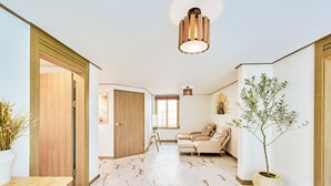 Een modern interieur met een marmeren vloer, een houten deur, een beige bank en een potplant.