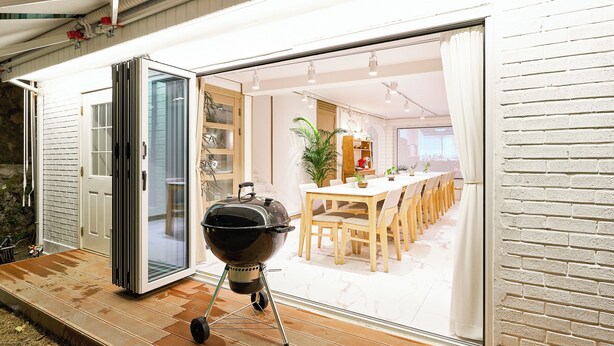 Een modern huis met een schuifglasdeur die leidt naar een eetgedeelte met een houten tafel en stoelen.