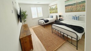 A bedroom with two beds, a wooden bench, a large window with blinds, and a painting on the wall. - Airy Desert Getaway  (Indio)