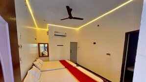 Una habitación de hotel con una cama grande, un ventilador de techo y una lámpara moderna.