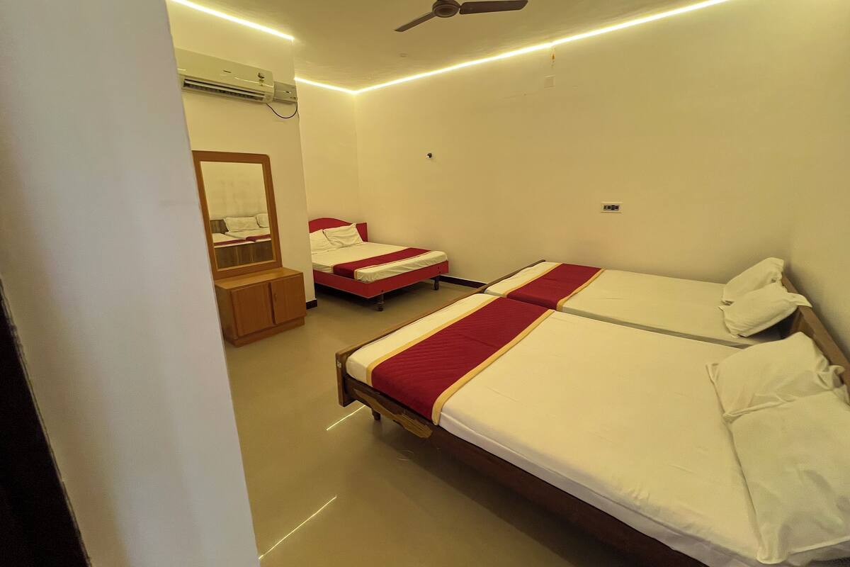 Ein Hotelzimmer mit zwei Einzelbetten, einem Holzschrank, einem Spiegel und einem Deckenventilator.