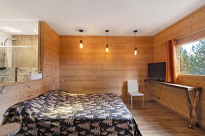 Un intérieur en bois avec un lit, un téléviseur et une fenêtre avec des rideaux.