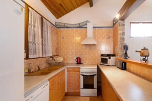 A compact kitchen with a dishwasher, stove, microwave, and wooden cabinets.