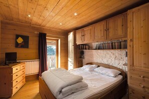 A wooden-paneled bedroom with a bed, a dresser, a television, and a bookshelf.