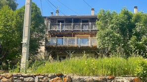 A two-story building with a balcony and a stone wall in front.