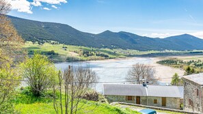 A rural landscape with a river, mountains, and a small building with a stone roof. - Village House Puyvalador: Mountain Charm, Breathtaking Views of Lake Puyvalador (Puyvalador)