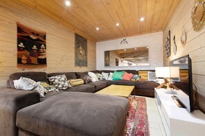 A cozy living room with a sectional sofa, a coffee table, and a flat-screen TV.