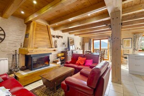 A cozy living room with a fireplace, leather sofas, and a stone wall.