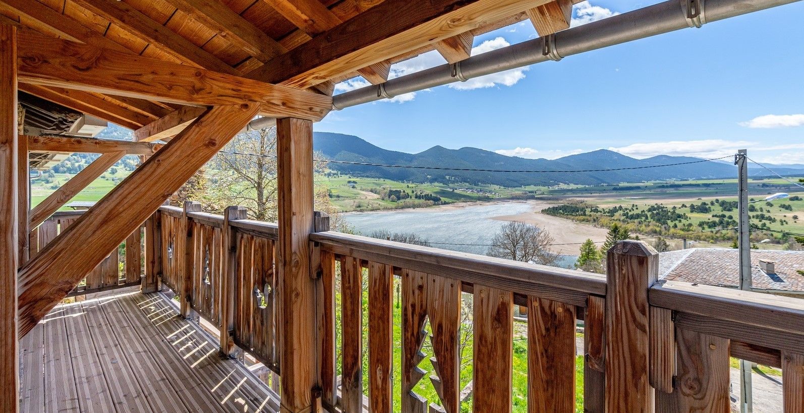Une terrasse en bois offrant une vue sur une rivière et des montagnes.