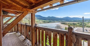 A wooden deck with a view of a river and mountains.