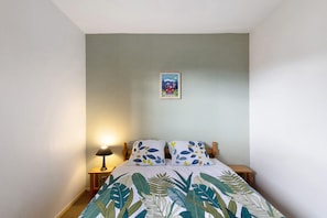 Une chambre à coucher avec un lit, une table de chevet, une lampe et un tableau accroché au mur.