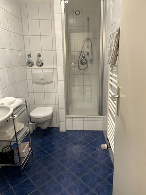 A bathroom with a shower, toilet, and sink.
