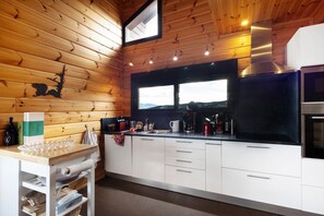 Een moderne keuken met houten wanden, een roestvrijstalen afzuigkap en een raam met uitzicht op een bergachtig landschap.