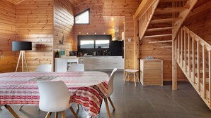 A wooden interior with a dining area, kitchen, and staircase. - Chalet Les Lupins in Les Angles – 6-8 guests, panoramic view, terrace, 10 min from ski slopes (Les Angles)