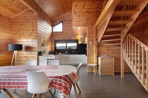 Un interior de madera con comedor, cocina y escalera.