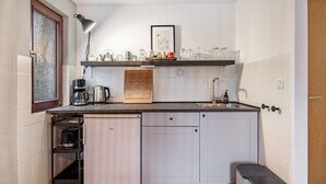 Cocina compacta equipada con lavavajillas, cafetera y refrigerador pequeño.