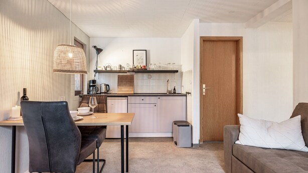 Un espacio habitable compacto con comedor, kitchenette y sofá.