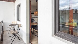 A small balcony with a table and chairs, a view through a window, and a door leading to a room with a table and chairs. - Apartment 'Hochwald' with Shared Terrace, Shared Garden and Wi-Fi (Bad Sachsa)