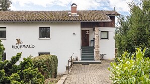 A building with a tiled roof, a sign reading 'HOCHWALD,' and a stone pillar. - Apartment 'Hochwald' with Shared Terrace, Shared Garden and Wi-Fi (Bad Sachsa)