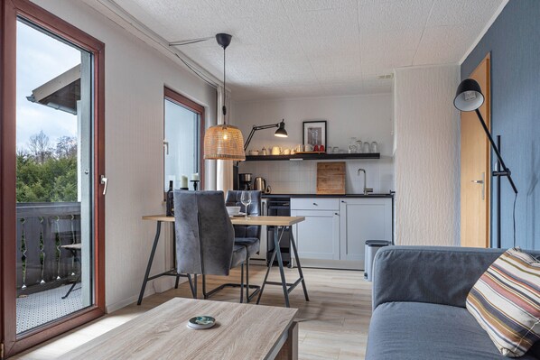 A modern apartment with a dining area, kitchen, and a balcony.