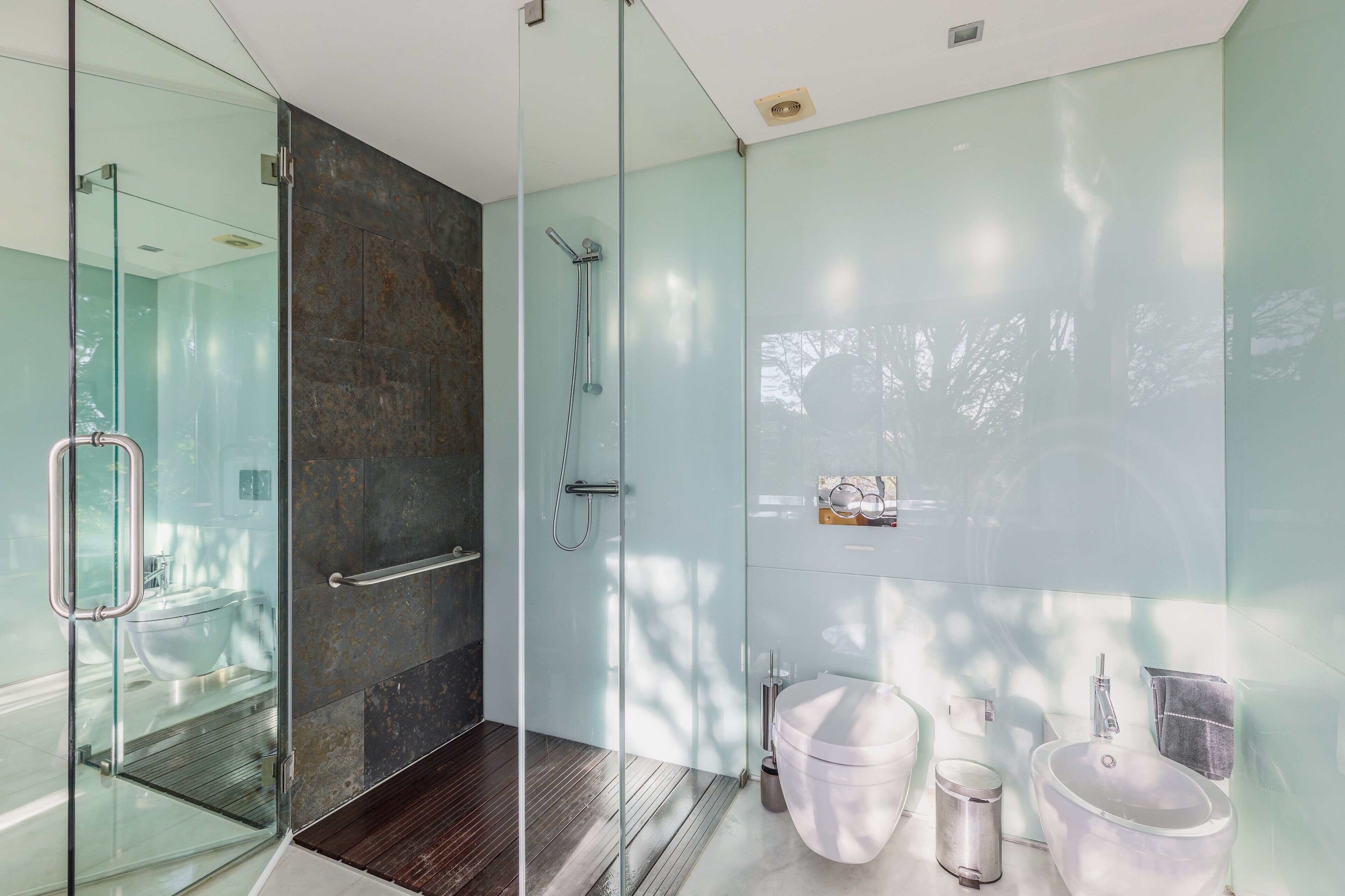 Un baño moderno con cabina de ducha de vidrio, inodoro blanco y lavamanos.