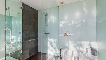 Un baño moderno con cabina de ducha de vidrio, inodoro blanco y lavamanos.