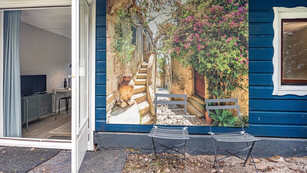 A blue house with a mural of a garden scene, a door, and a bench outside. - Chalet 'Hochwald' with Shared Terrace, Private Garden and Wi-Fi (Bad Sachsa)