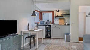 A compact living space with a kitchenette, a dining area, and a TV. - Chalet 'Hochwald' with Shared Terrace, Private Garden and Wi-Fi (Bad Sachsa)