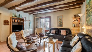 A living room with a fireplace, leather sofas, a television, and a bookshelf. - Country House 'Cal Contra' with Mountain View, Private Pool and Wi-Fi (Gelida)