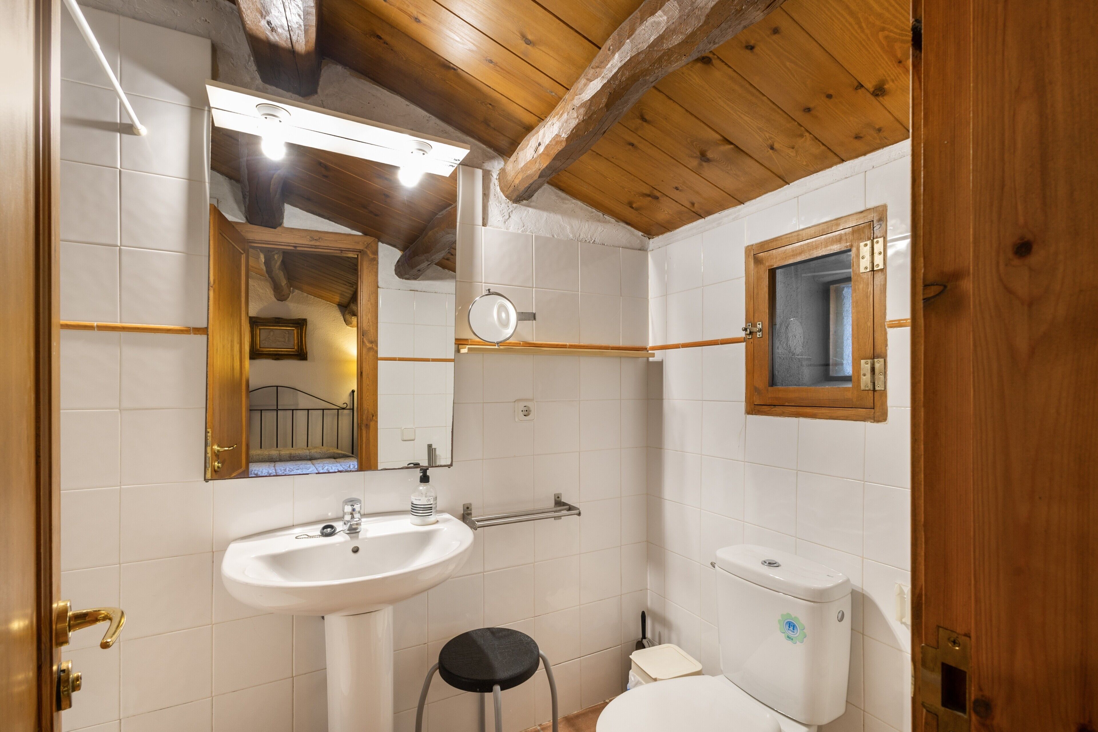 Une salle de bain avec un lavabo, des toilettes et un miroir, le tout de couleur blanche.