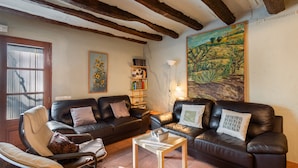 A living room with a fireplace, leather sofas, a wooden coffee table, and a bookshelf. - Country House 'Cal Contra' with Mountain View, Private Pool and Wi-Fi (Gelida)