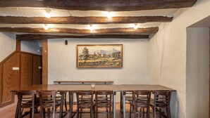 A dining area with a long wooden table, six chairs, and a painting on the wall. - Country House 'Cal Contra' with Mountain View, Private Pool and Wi-Fi (Gelida)