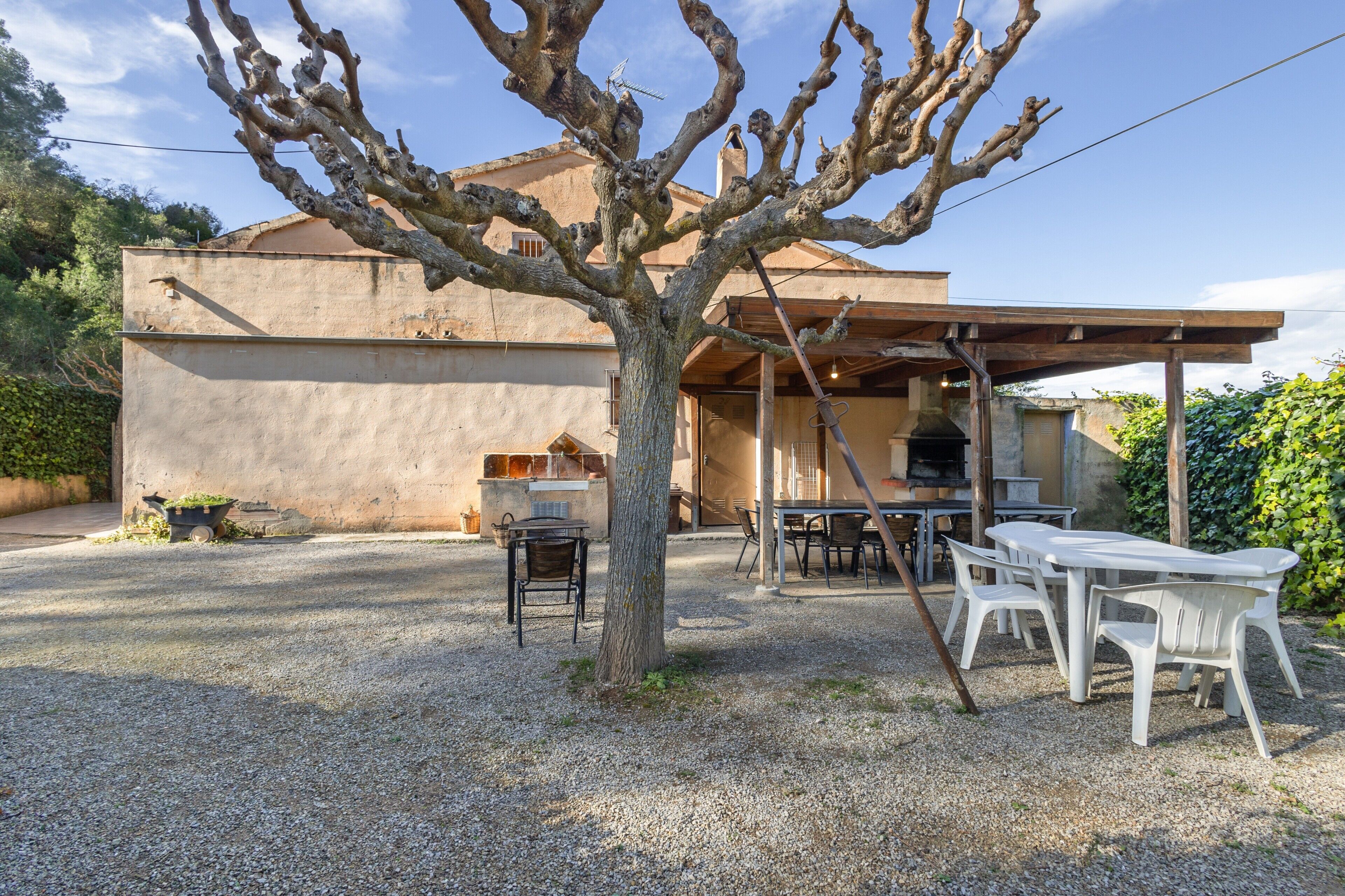 A house with a patio area, outdoor seating, and a barbecue setup.